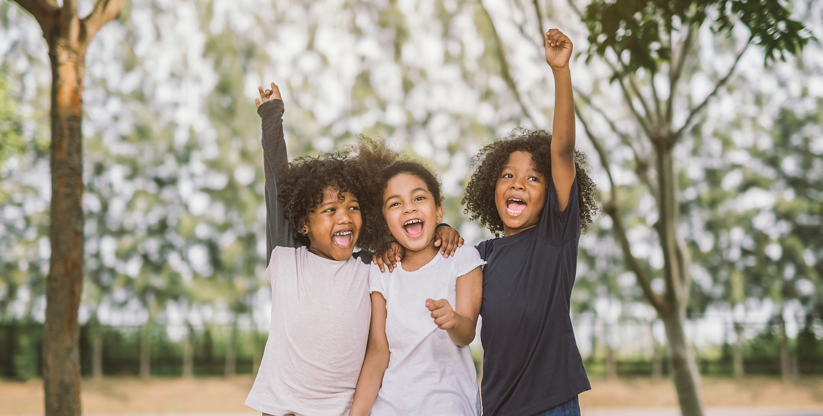 Three siblings pumping their fists in the air, celebrating together